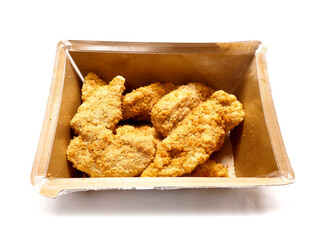 Uncooked chicken goujons or tenders in a card board box on white background. Popular classic chicken dish made from pieces of breast and breadcrumbs. Traditional ready to cook poultry product.