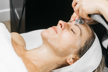 Woman receiving RF lifting facial rejuvenation treatment in a spa setting, with soothing ambiance...