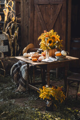 Cozy autumn composition near old wooden country house. Table setting for family thanksgiving dinner with homemade apple pie, bouquet of sunflowers, pumpkins. Elegant rustic cottage core home decor