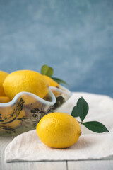 Vintage Bowl of Lemons with One in Front on White Table with Blue Background