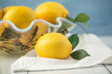 Vintage Bowl of Lemons with One in Front on White Table with Blue Background