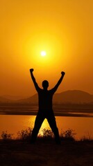 Fototapeta premium Silhouette of a person with arms raised high in pure triumph against a vibrant golden sunset, reflecting ultimate hope, success, and powerful new beginnings over calm water.