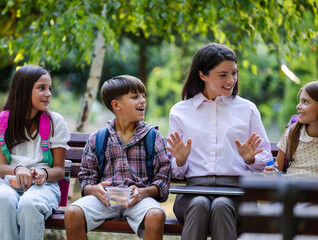 Teacher gets comfortable on a bench with pupils