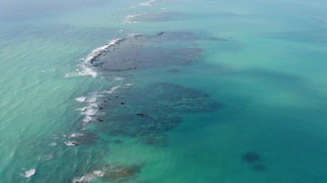 Aerial view of turquoise ocean water with coral reefs near the shore