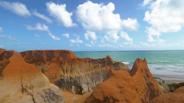 Beautiful cliffs meet the ocean under a bright blue sky with fluffy clouds