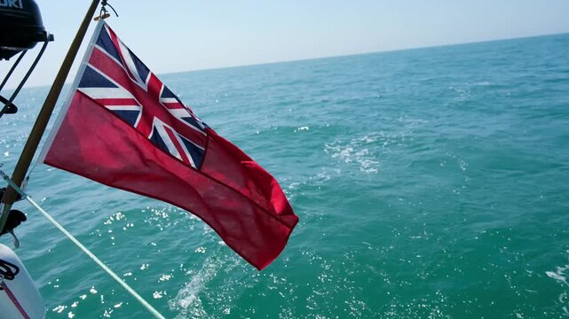 30 JUN 2025 - Solent, UK - The British Ensign Flag on the back of a sailing yacht flapping in the wind.