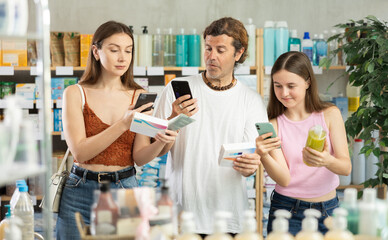 Man with wife and teen daughter in pharmacy scans QR code on drug store assortment items. Client uses link to go to manufacturers website.