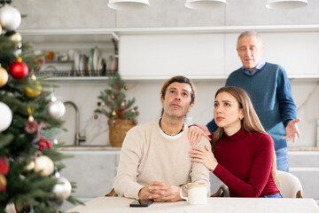 Elderly man quarreling with young woman and adult man in kitchen at home