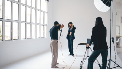 Photographer taking pictures of fashion model in professional studio