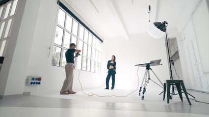 Photographer taking pictures of model posing in photo studio