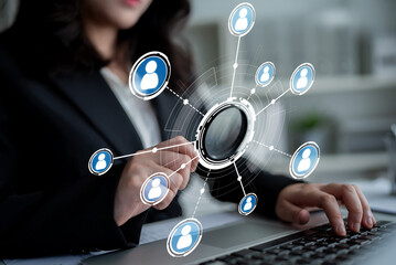 A businesswoman interacts with a laptop, exploring a visual network of connections, representing modern digital interactions and professional relationships in a sleek office setting. Crux