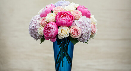 A breathtaking bouquet of pink peonies, white roses, and lavender hydrangeas, a vibrant celebration of spring's beauty in a sleek blue vase.