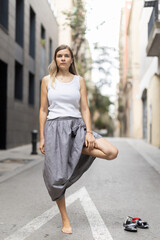Fototapeta premium Female citizen in casual clothes perform tree yoga asana. Woman chose deserted urban highway for yoga break