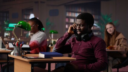 Rude man answering a phone call in the library and disturbing people, being very noisy. Students asking to keep quiet, losing focus and concentration while learning or reading. Camera A.