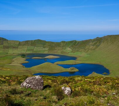 Panoramic view of the Caldeirao volcanic caldera with blue crater lakes on Corvo Island, Azores, Portugal; Atlantic Ocean in the distance, no people