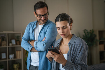 Man spying on woman using smart phone in relationship problems