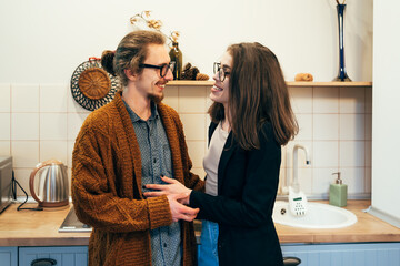 Happy couple smiling and holding hands in cozy kitchen, enjoying warm moment together in casual home environment.