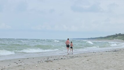 A father and son enjoy a playful day at the beach, running in the surf and creating cherished memories.