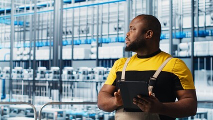 Photovoltaics smart factory specialist analyzing data using tablet. African american man in industry 4.0 solar panels plant producing renewable energy using notebook to review system metrics, camera A