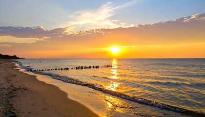 Serene sunset over sandy beach with golden reflections in wavy water