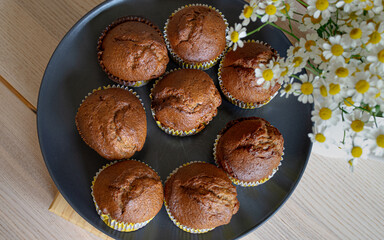 Freshly baked homemade chocolate muffins on plate with flowers, cozy family baking scene