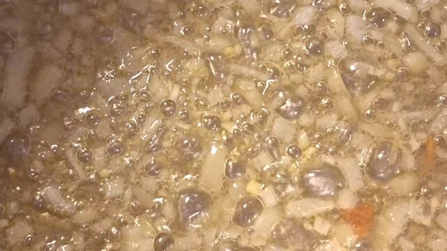 Bubbling hot oil frying chopped onions