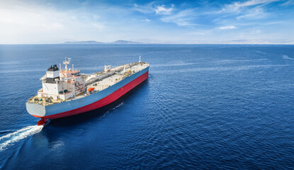 Fototapeta premium Aerial rear view of a large crude oil or chemical goods super tanker traveling vcer the ocean with copy space