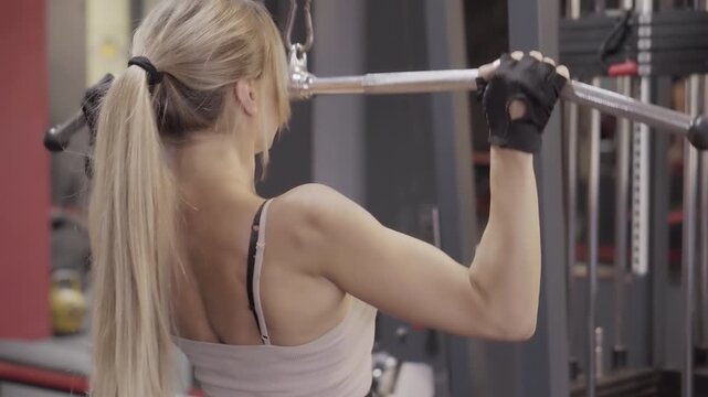 Upper Body Workout: Focused female athlete using a cable machine for seated lat pulldown