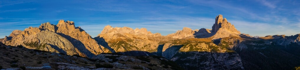 Panorama of Alps mountains on a sunny day. High resolution widescreen panorama of mountain landscape. Blue sky with some clouds above beautiful summits alpine range Dolomite Alps in Italy