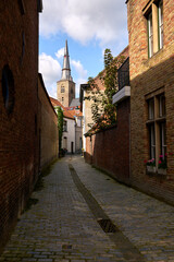 St Anne`s Church Bruges Alley Belgium. The spire of St Anne`s Church at the end of an alley in Bruges, Belgium. 
