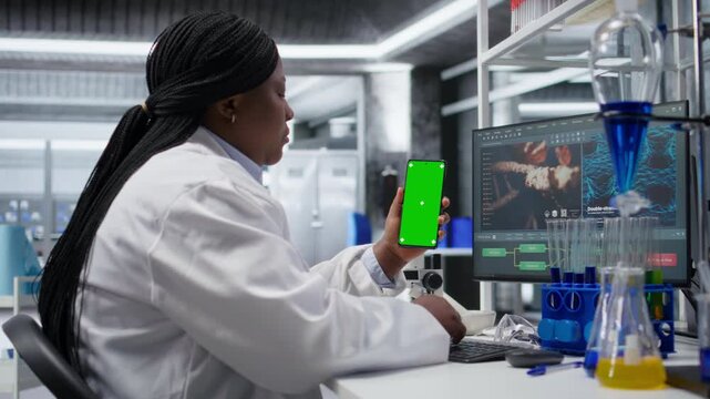 Mockup screen on smartphone used by chemistry expert with laboratory tech at biolab desk, focusing on genetics research, nanotechnology and data for medical discovery and innovation. Camera A.