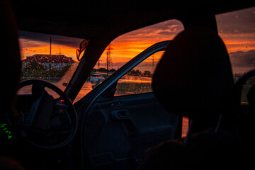 view from a car on the highway in bad weather conditions, rain and fog, at a beautiful red sunset