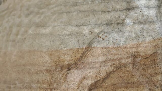 Natural sand water ripple texture pattern beach shore with layered sandstone geology, sedimentary strata, mineral grain, rough surface earth tone