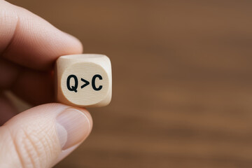 Quality cost balance concept with wooden cube held by hand symbolizing importance of quality over cost in decision making for better balance