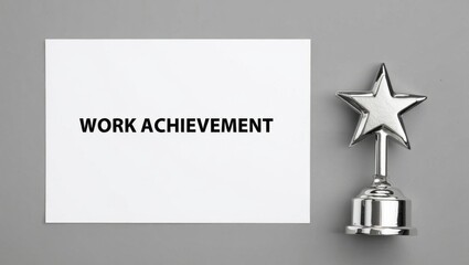 Work Achievement text on paper with star trophy on grey background