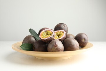Fresh passion fruits with green leaves on white table