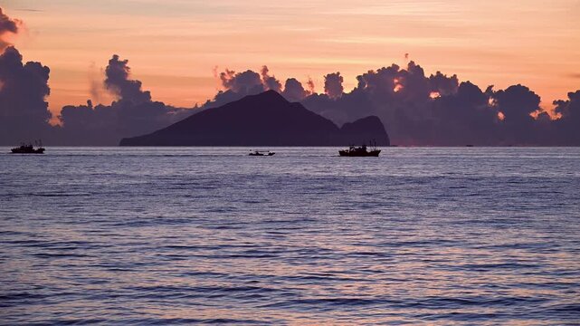 Fishing boats crosses the ocean at predawn near Guishan Island off the Zhuangwei coastline in Yilan Taiwan The sky displays beautiful orange pink and blue hues
