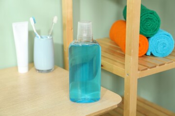 Bottle of mouthwash on wooden shelf in bathroom