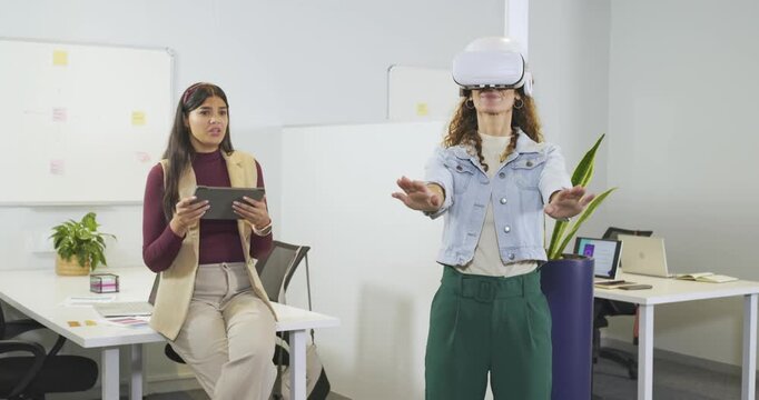 Diverse female coworkers facilitating VR demo using tablet and guiding user gestures in office