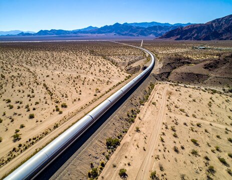 Aerial drone shot of hyperloop tunnel cutting across desert landscape.