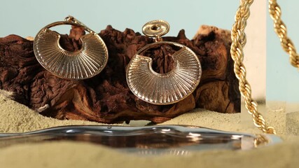 Stylish presentation of beautiful gold jewelry on sand, closeup