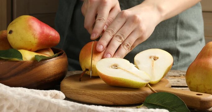 Woman cutting fresh pears at wooden table, closeup