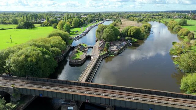 Aerial view of canal lock gate system on River Trent, narrow boat vacation and infrastructure, rolling green rural landscape sunny evening near Nottingham, United Kingdom