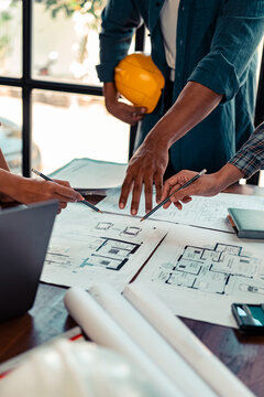 Architect checking blueprints on construction site Architects and engineers meet to discuss and check house plans to meet building and construction standards.