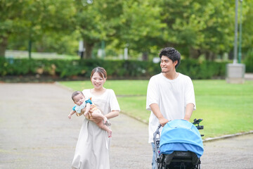 Obraz premium A young couple is walking with a baby in a stroller. The baby is wearing a blue shirt
