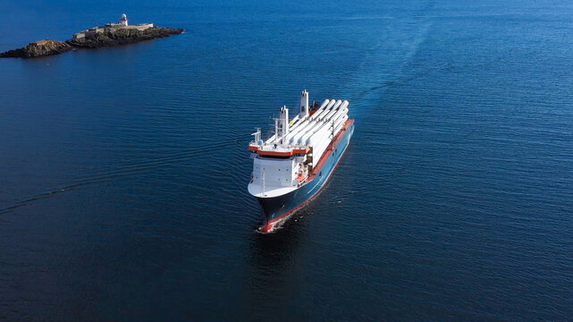 A ship sailing across the sea transporting parts of large wind turbines for sustainable energy generation