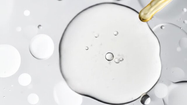 Golden elixir pipette adding concentrated fluid to a clear viscous gel, forming captivating