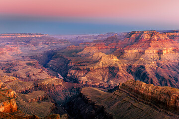 Grand Canyon South Rim with Colorado River at sunrise, golden light on cliffs, deep shadows, colourful sky, dramatic landscape.
