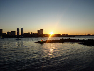 Fototapeta premium A breathtaking city view through the river, where the skyline reflects on calm waters and the urban lights blend with nature’s serenity. This scene captures the harmony between city life and natural
