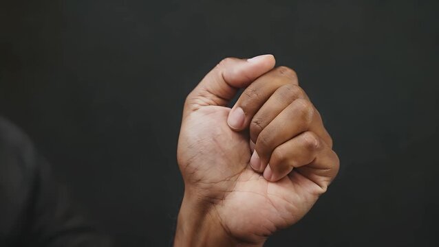powerful and strong clenched human fist raised up high and isolated on pure solid black background, representing strength and defiance